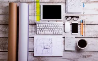 Desk with gadgets and office supplies for managing a household move. Computer keyboard, smart phone, tablet, and various things around the workplace.
