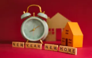 New Year, New Home, with an alarm clock, miniature houses, and wooden blocks spelling out "New Year, New Home" symbolizing new beginnings and fresh starts, Real estate, moving, and new year's concept