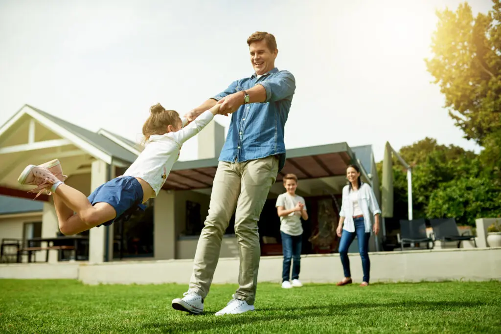 Backyard, family and father swinging child in home garden for bonding, connection and fun together. Happy, love and dad spinning and playing with girl kid on weekend outdoor of house in summer