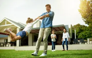 Backyard, family and father swinging child in home garden for bonding, connection and fun together. Happy, love and dad spinning and playing with girl kid on weekend outdoor of house in summer