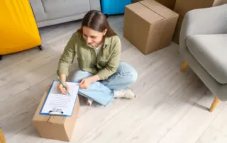 Young woman making checklist in room on moving day