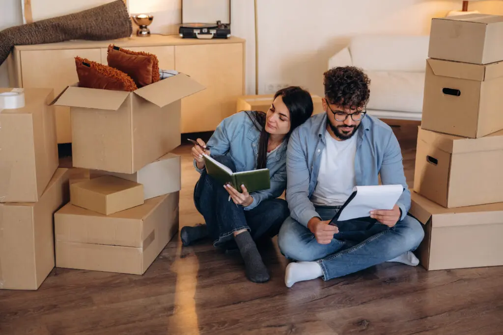 Notepad is in hands. Couple reviewing documents and planning their new home after moving.