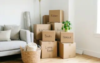 Numerous cardboard boxes labeled with room names and 'Fragile' are stacked neatly in a home interior, showcasing the organized chaos of relocation and unpacking, perfect for moving services.