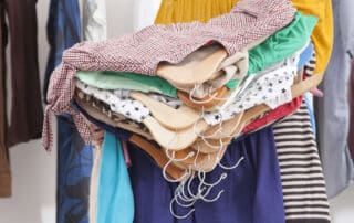 woman holding many clothes on hangers from closet