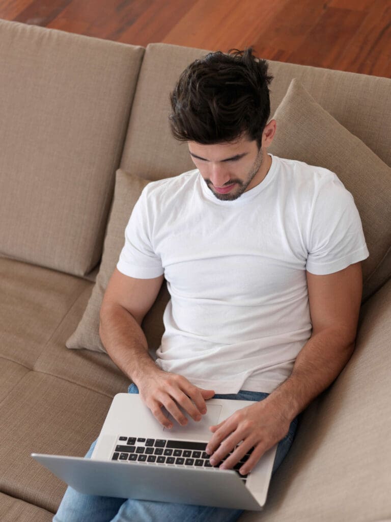 Man on sofa with laptop calculating moving costs