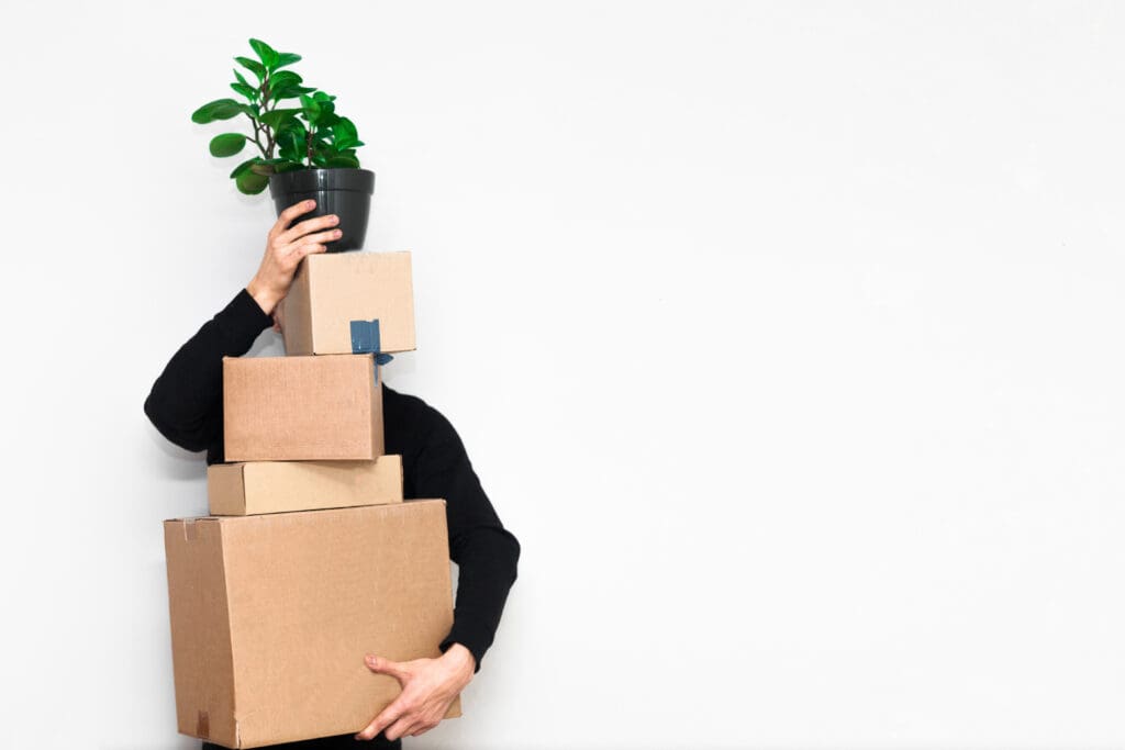 Man with box moving in holding a plant