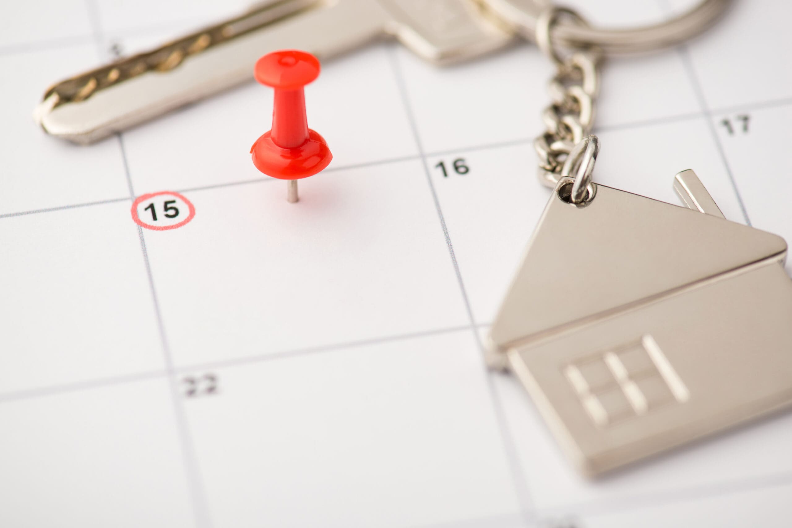 Overhead photo of label date 15 with inscription move house red pin and key with key ring as house isolated on the calendar background