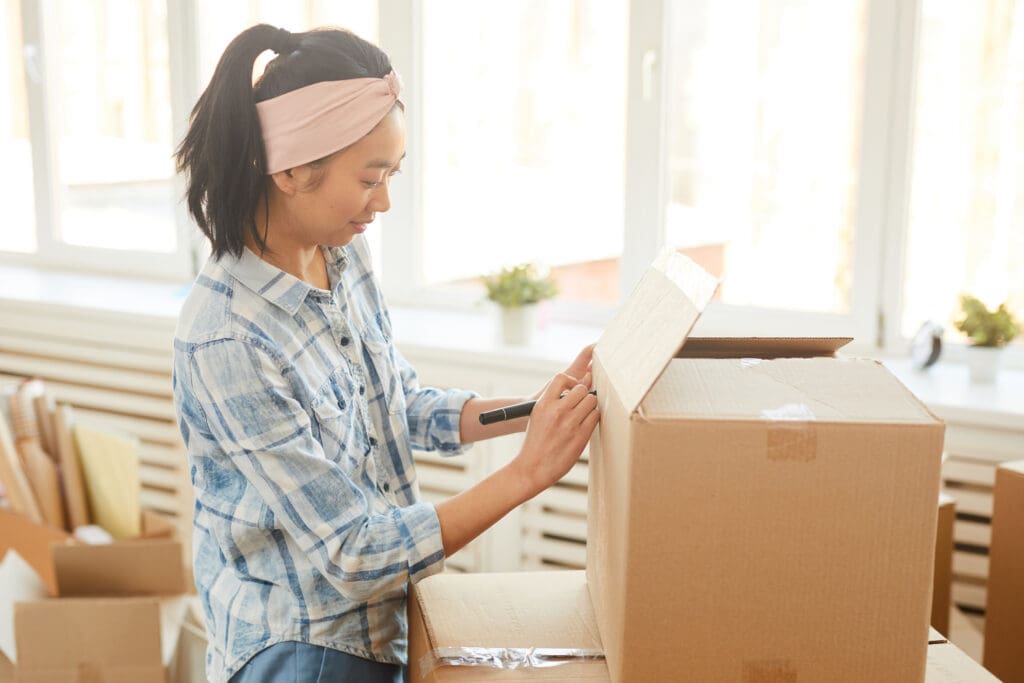 Woman labeling essentials kit moving box