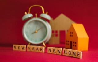 New Year, New Home, with an alarm clock, miniature houses, and wooden blocks spelling out "New Year, New Home" symbolizing new beginnings and fresh starts, Real estate, moving, and new year's concept