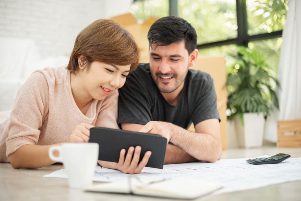 Happy young couple with digital tablet planning budget for household move.